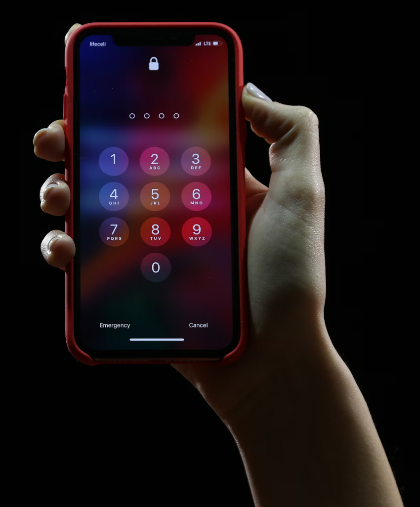 Hand holding mobile phone with keypad to enter PIN